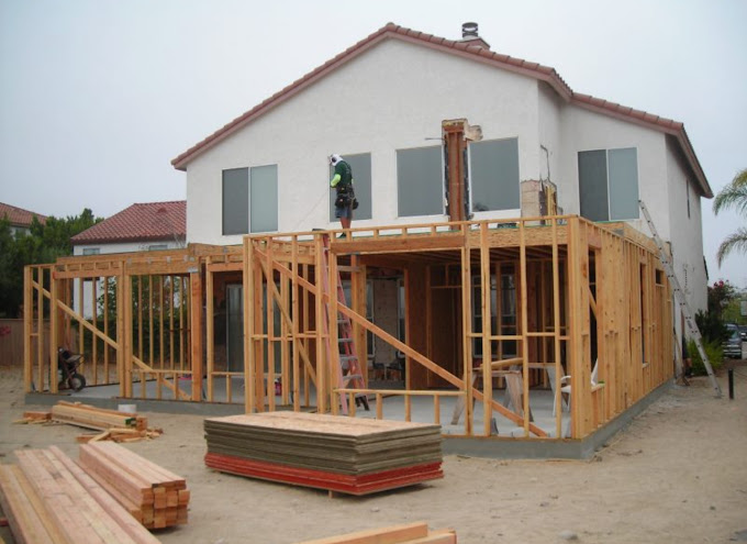 A house under construction with a man standing on the roof